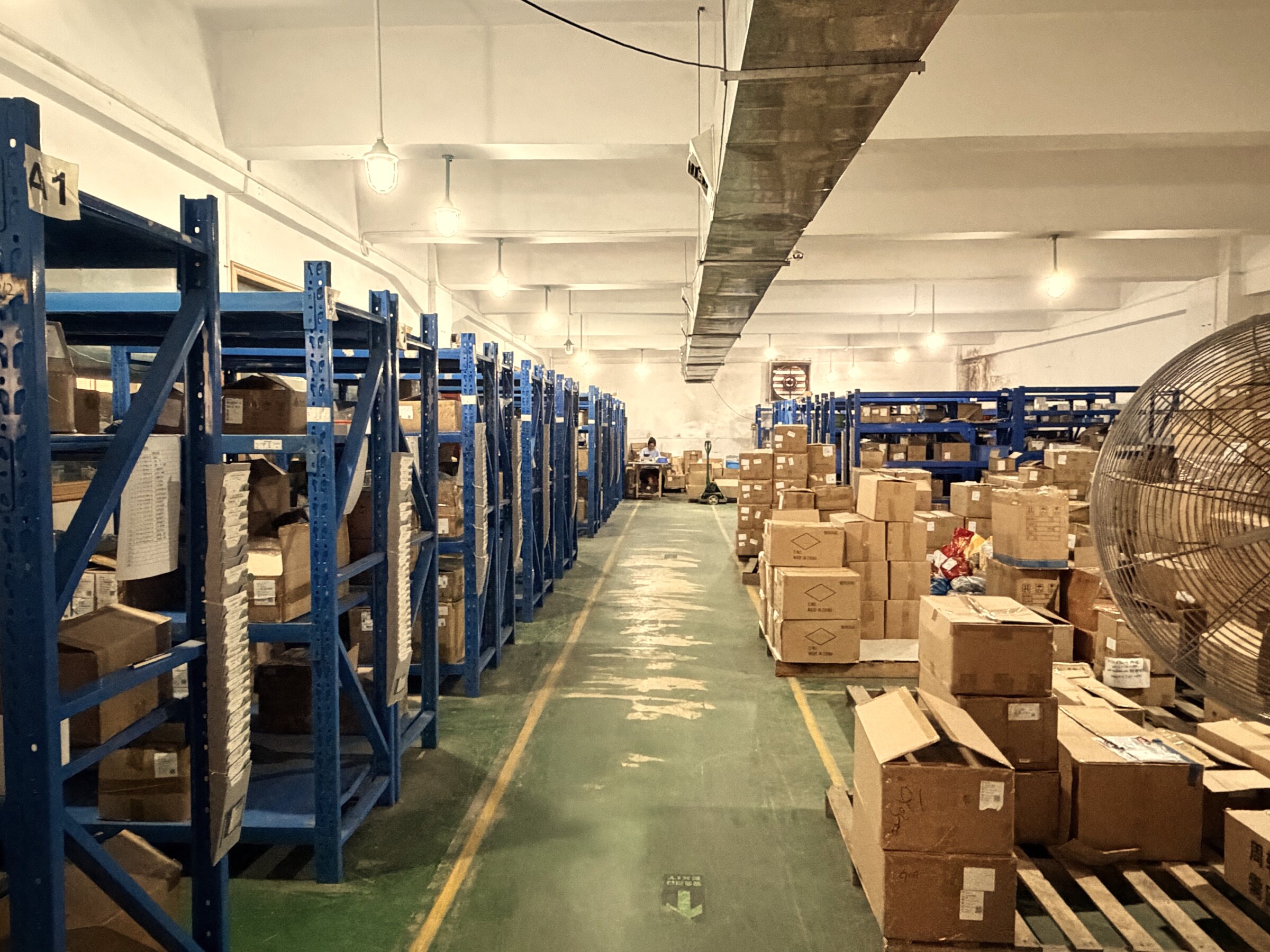 Components and materials warehouse — blue racking holds every part used across the 28 electric towel warmer models