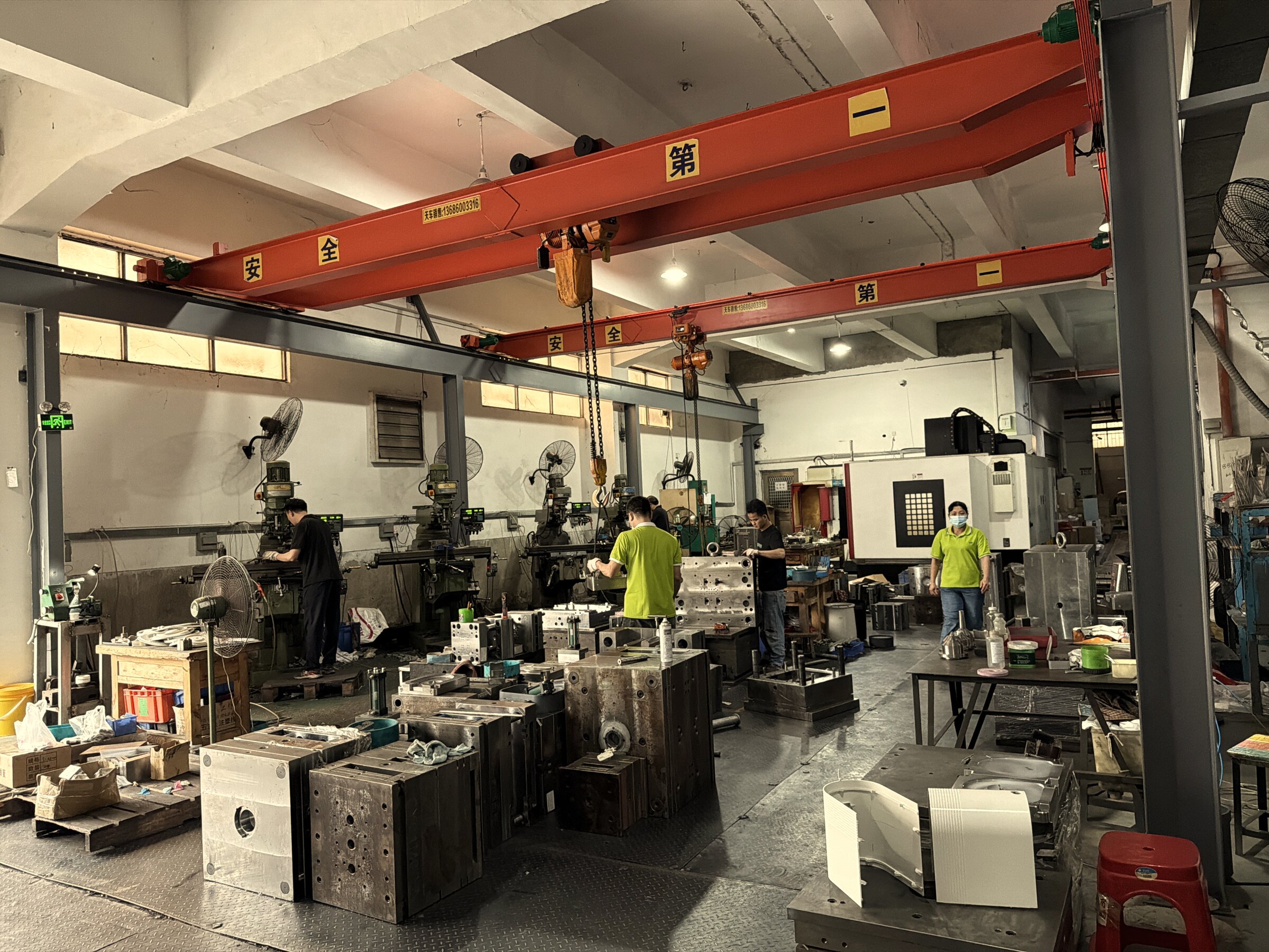 In-house tooling and mold workshop where every custom OEM towel warmer tool is cut — overhead gantry crane, CNC bench, machinists fitting injection-mould halves